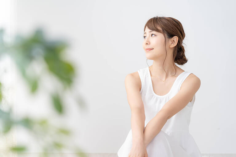 横を向く白いワンピースを着た女性